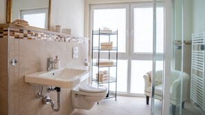 Ein modernes Badezimmer mit Waschbecken, Toilette und einer Duschkabine aus Glas.