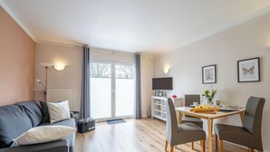 Ein modernes Wohnzimmer mit einer Couch, einem Esstisch mit Stühlen, einem Fernseher und Kunstwerken an der Wand.