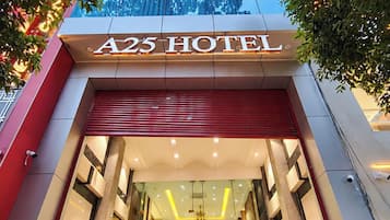The entrance of A25 Hotel with a red awning, glass doors, and a staircase leading to the lobby.