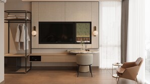 Habitación de hotel moderna con un televisor de pantalla plana grande, encimera de mármol, zona de estar con una silla y armario con ropa colgada.