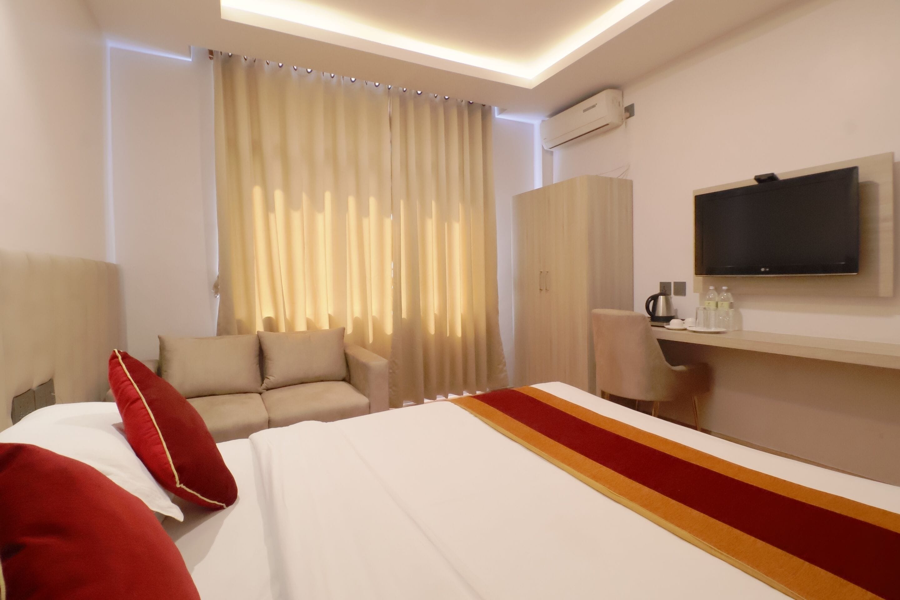 A hotel room with a bed, a sofa, a TV, and a desk.