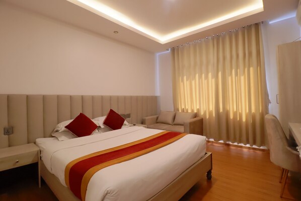 A hotel room with a large bed, a desk, and a chair. - Palagya Hotel (Kathmandu)