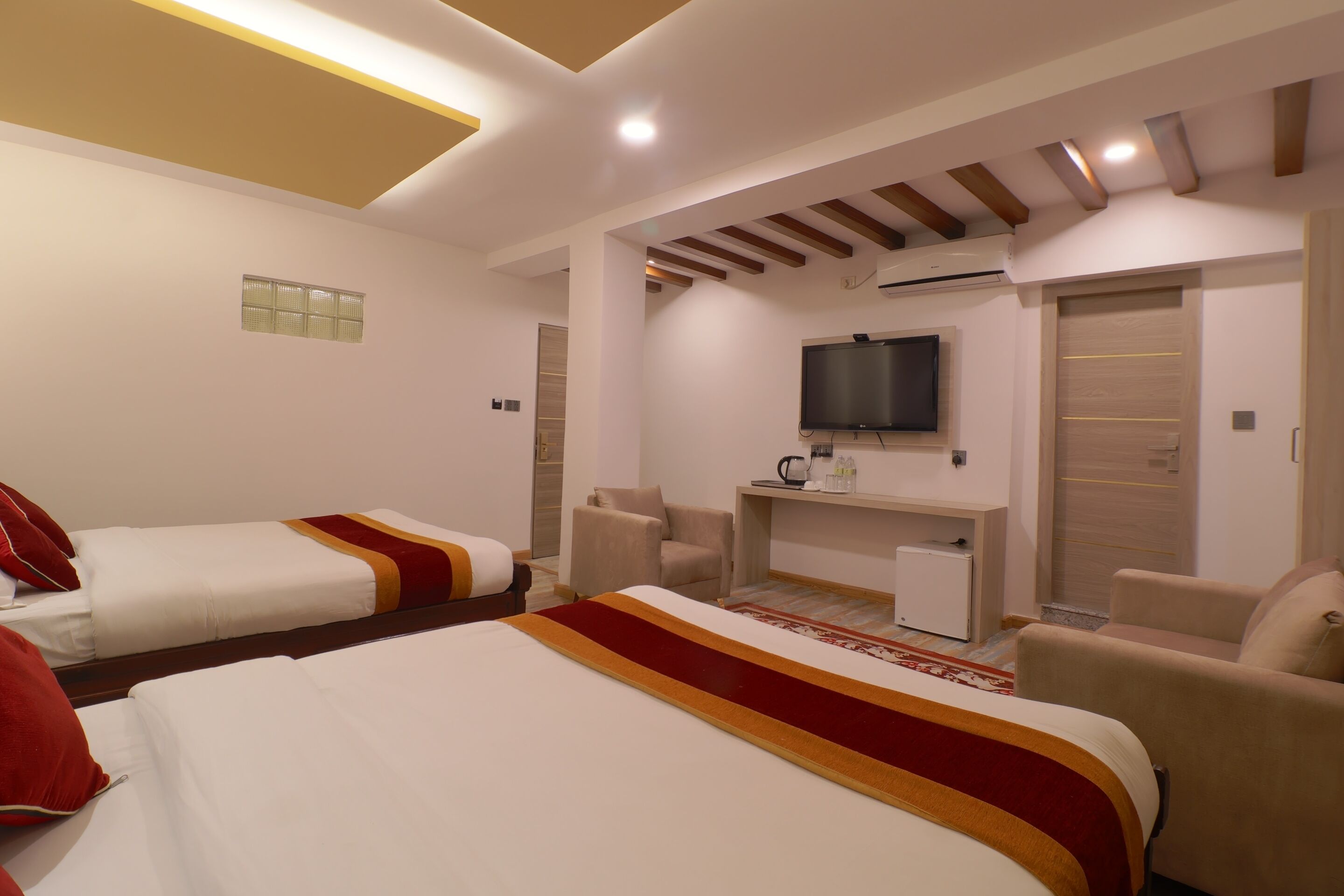 Ein Hotelzimmer mit zwei Betten, einem Fernseher, einem Schreibtisch und einem Sessel.