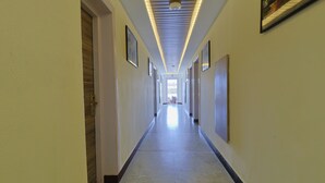 A long, narrow hallway with a tiled floor and a series of doors on one side.