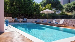 Una piscina con sillas de descanso y una pérgola.