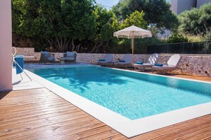 Ein Schwimmbecken mit Liegestühlen und einer Pergola.