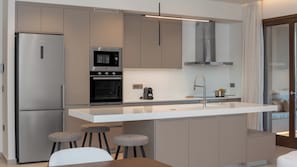 A modern kitchen with a central island, stainless steel appliances, and bar stools. - VaMa Luxury Living-8BR Design Villa with Heated Pool and Playroom (Episkopi Rethymnou)