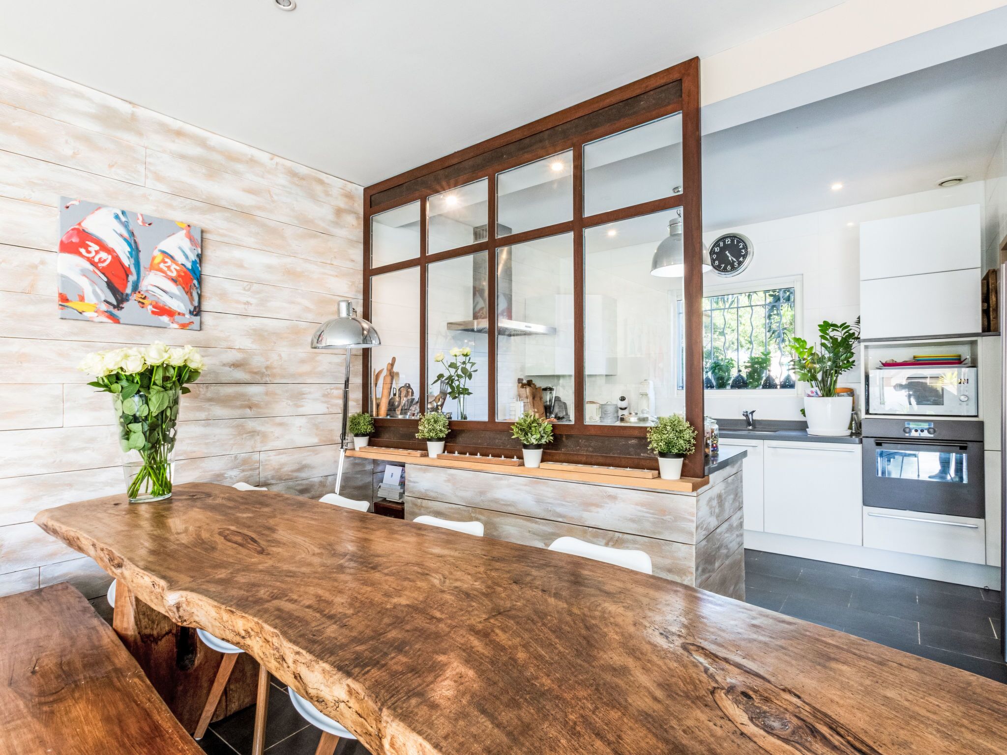 A modern kitchen with a wooden island, white cabinetry, and a large window.