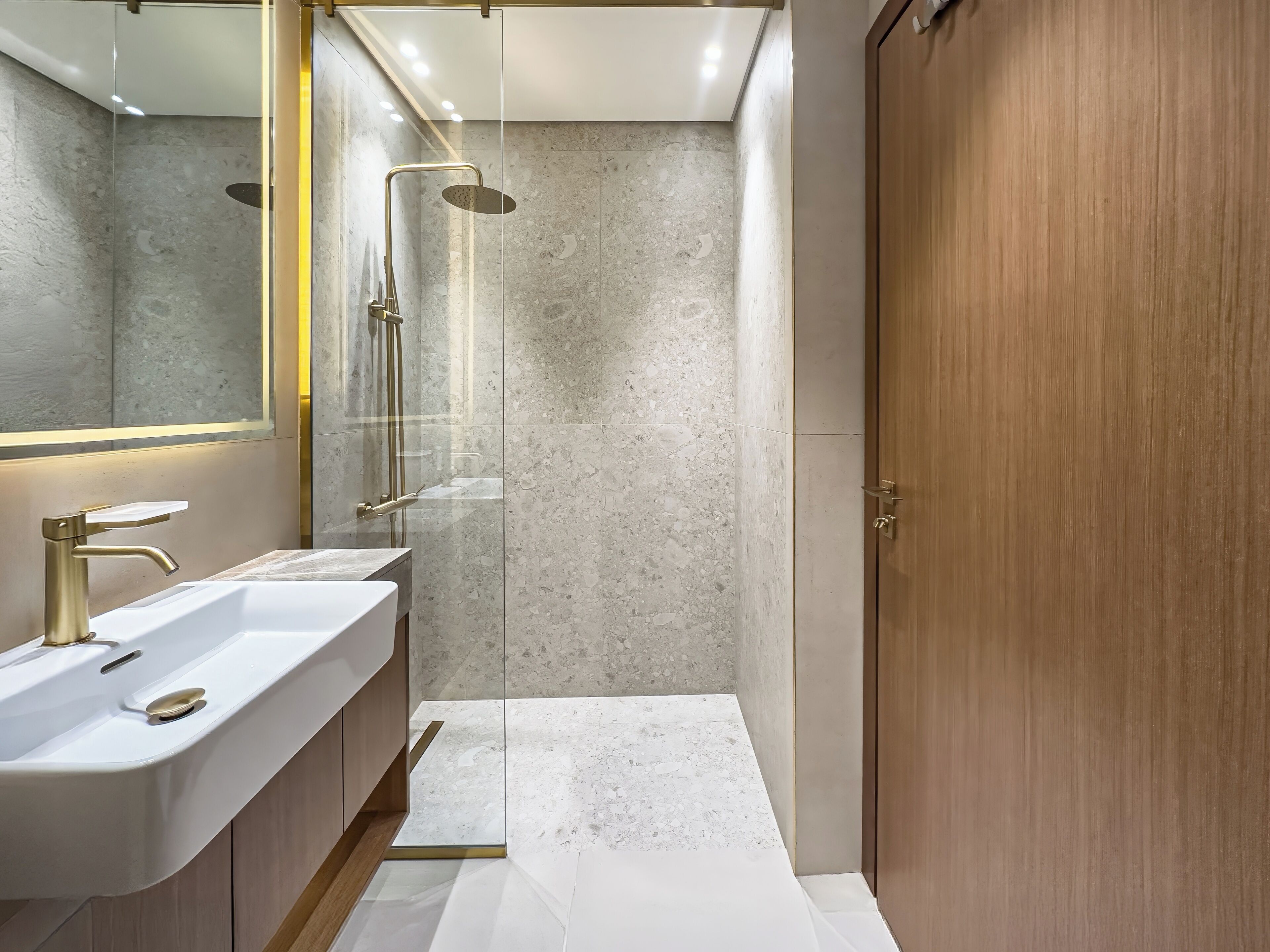A modern bathroom with a dual sink vanity, a glass shower enclosure, and a wooden wardrobe.