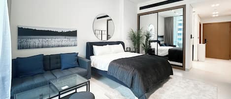Une chambre moderne avec un lit, un canapé, une table en verre et un miroir.