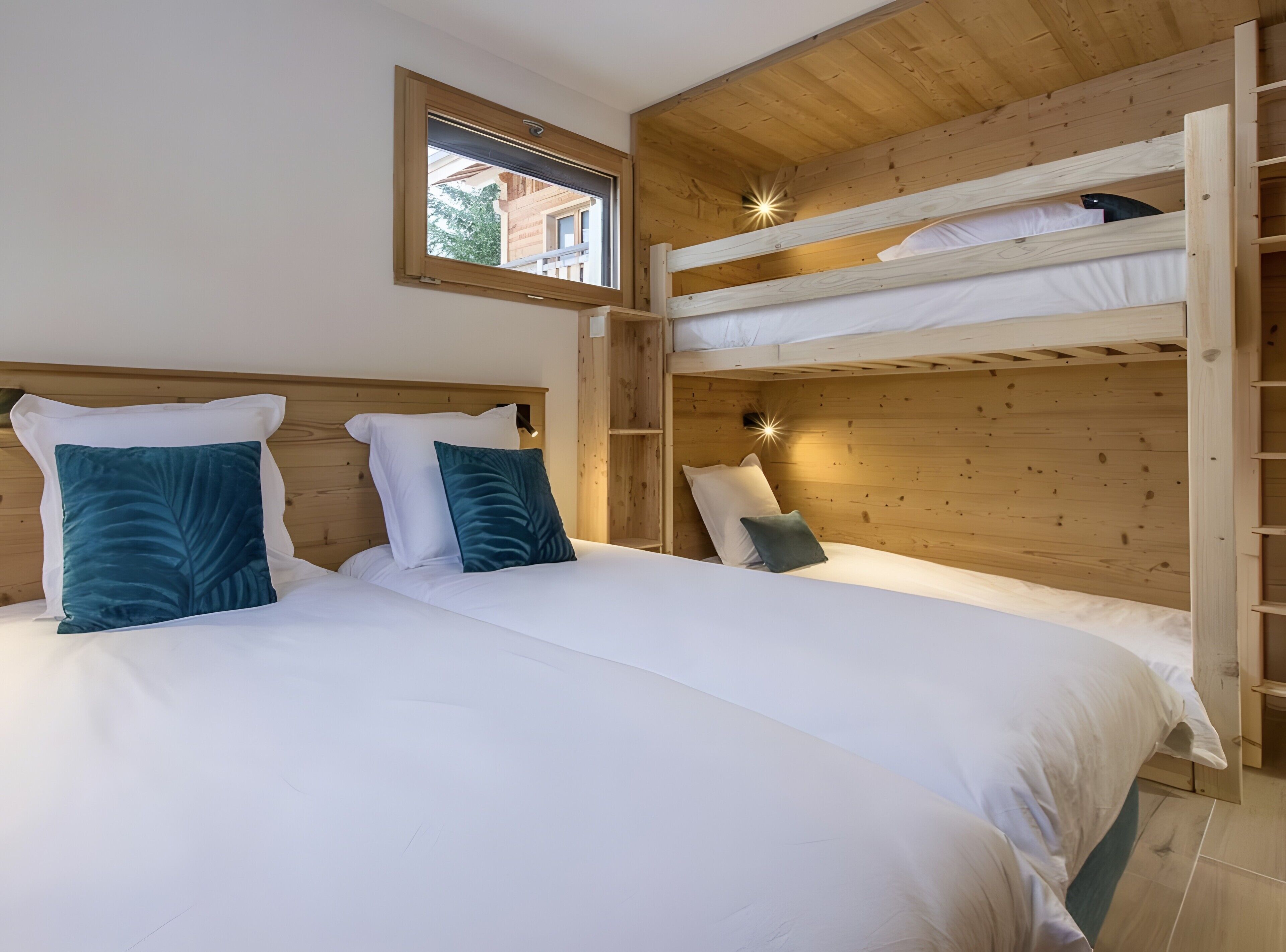 Une chambre avec un lit superposé, deux lits simples, une fenêtre et des murs en bois.