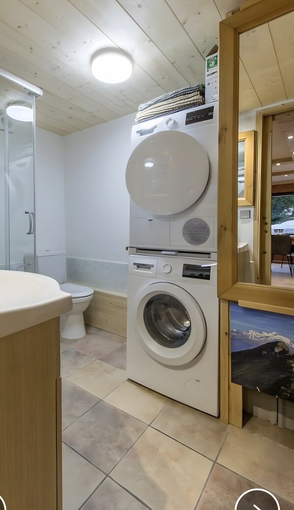 Ein kleines Badezimmer mit Toilette, Waschmaschine und Spiegel.