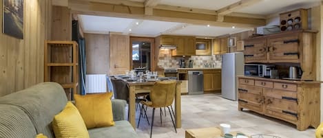 A modern kitchen with wooden cabinets, a dining area with a sofa and chairs, and a kitchen island with a microwave and coffee maker.