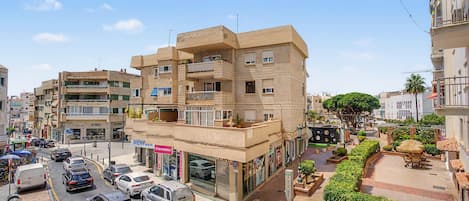 A multi-story building with a ground-level retail space, a visible storefront, and a street with parked cars.