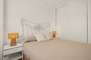 A neatly made bed with a headboard, two bedside lamps, and a bedside table with a drawer. - Central Apartment 'Apto Anabel Nerja' (Nerja)