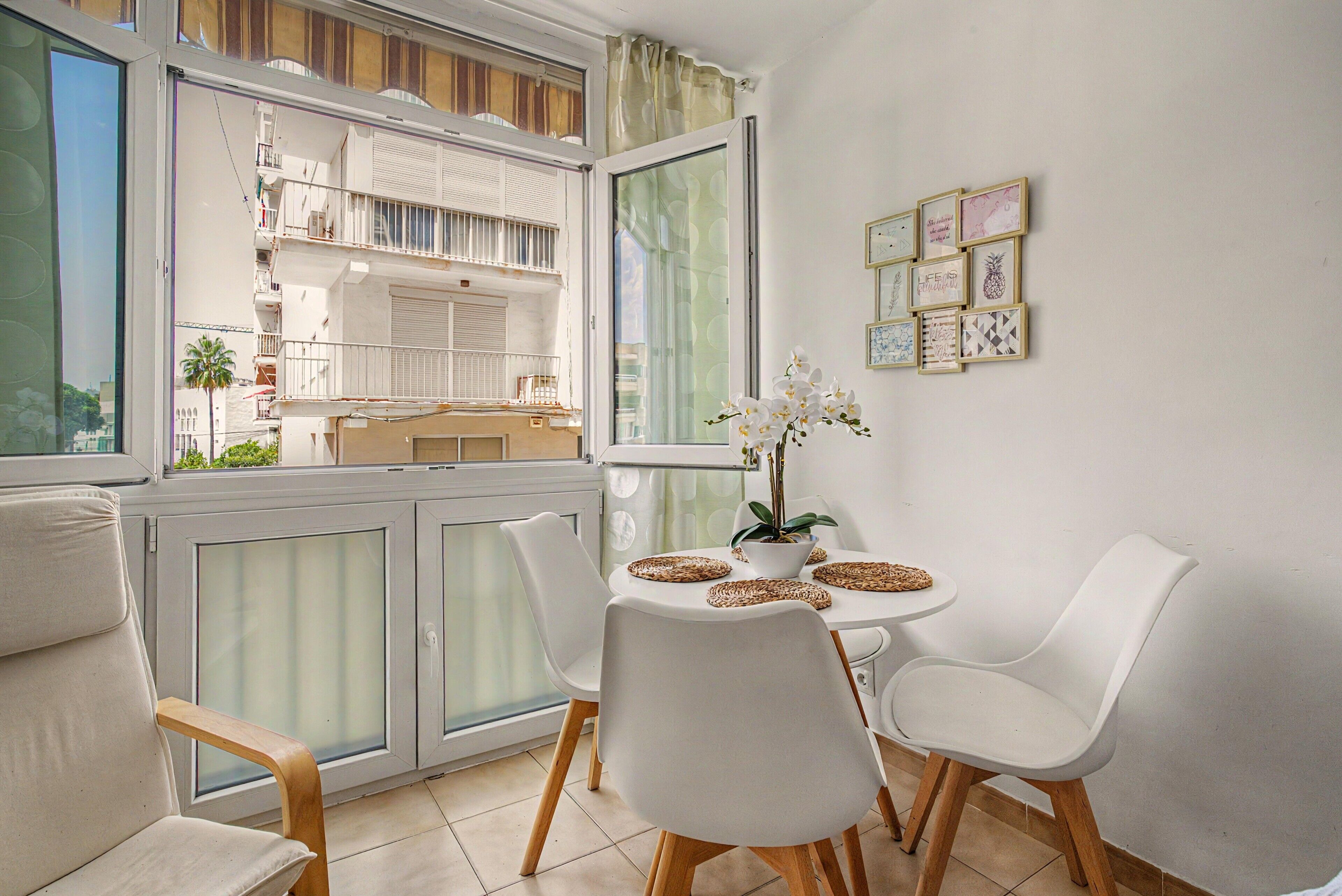 Een balkon met een eettafel, stoelen en een potorkidee.