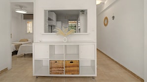 Un saló modern amb una console blanca, un mirall gran i cistos de vimet.