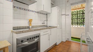 Cuina amb armaris blancs, forns d'acer inoxidable i un taulell de granat.