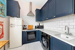 Eine kompakte Küche mit Waschmaschine, Geschirrspüler und eingebautem Backofen.