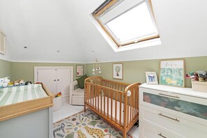 Ein Kinderzimmer mit einem Babybett, einer Wickelkommode und einer Anrichte.