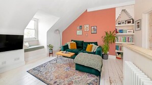 Uma sala de estar moderna com um sofá verde, uma mesa de centro e um tapete estampado.