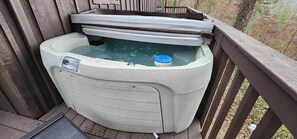 Ein Whirlpool auf einer Holzdielen Terrasse, mit Bedienfeld und blauem Deckel.