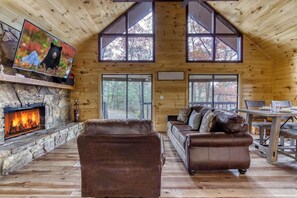 A cozy cabin interior with a stone fireplace, leather sofas, and large windows. - Baby Bear-Get $560 worth of FREE area attraction tickets for each paid day!!! (Sevierville)