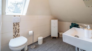 Ein kleines Badezimmer mit Toilette, Waschbecken, Schrank und Fenster.