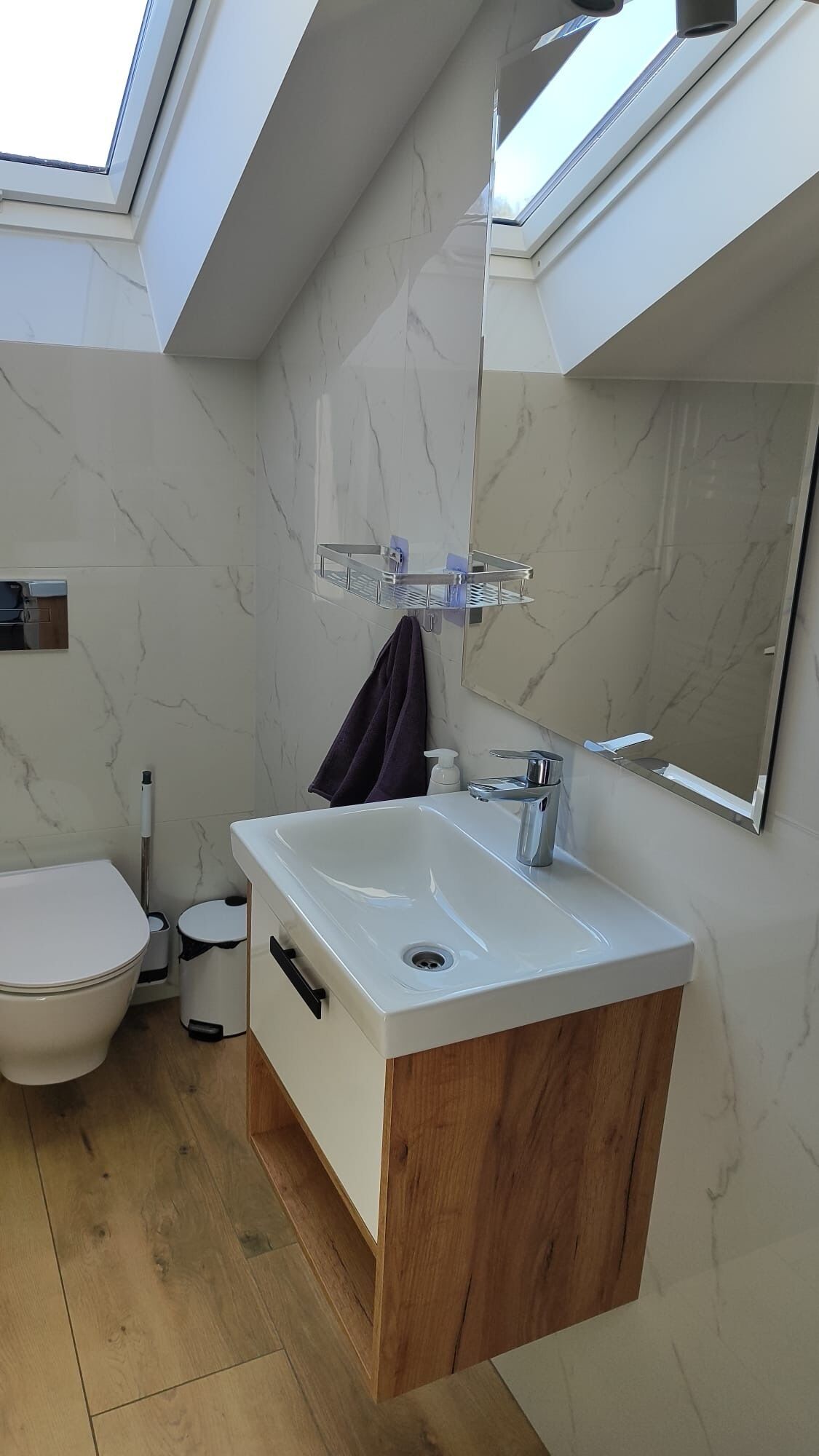 Un bany modern amb una finestra de sostre, un lavabo de fusta, un lavabo blanc i un vàter.