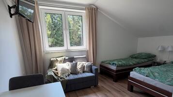 A room with a bed, a sofa, a table, and a window.