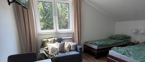 Una habitación con cama, sofá, mesa y ventana.