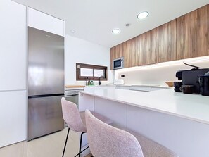 Uma cozinha moderna com uma geladeira de aço inoxidável, micro-ondas e máquina de café.