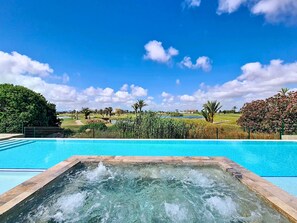 A swimming pool with a hot tub in the foreground and a golf course in the background. - Ground Floor Oasis at La Serena Golf (Los Alcazares)