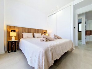 Een moderne slaapkamer met een groot bed, twee nachtkastjes met lampen, en een houten hoofdeinde.