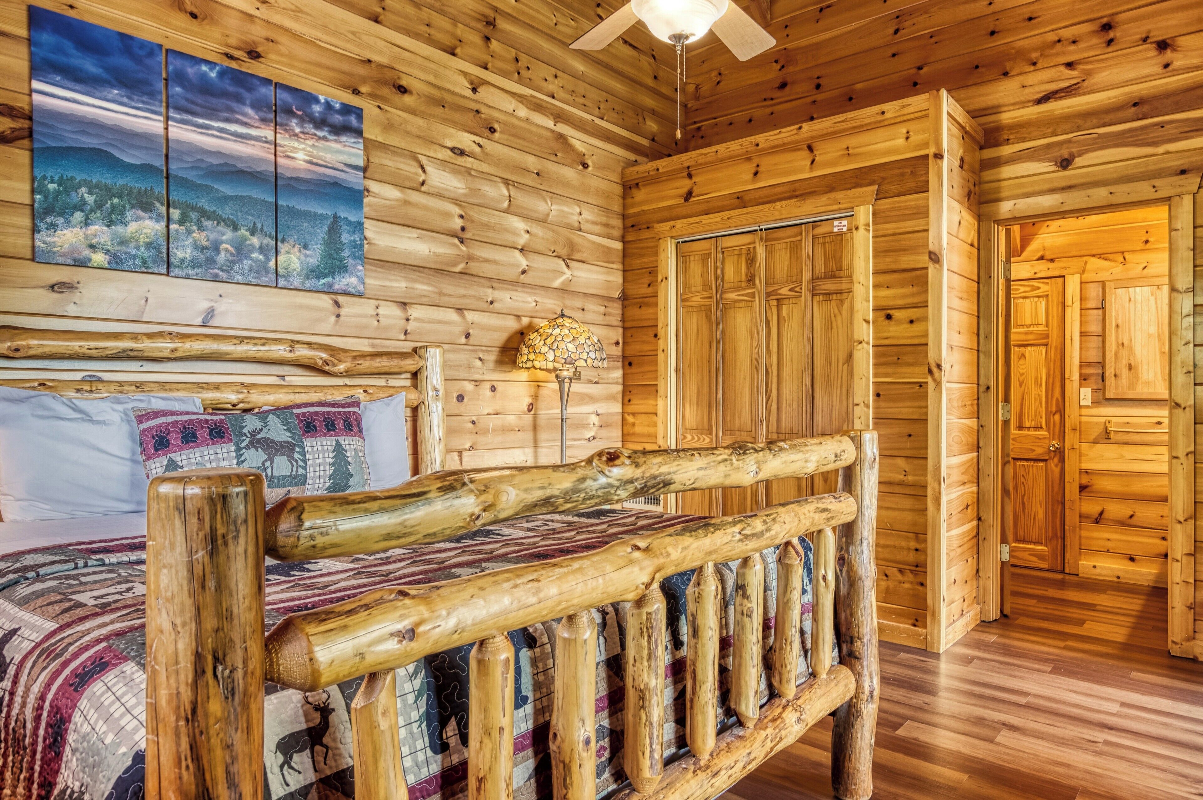 Ein Holzblockhaus-Interieur mit einem Bett, einem Gemälde, einer Lampe und einem Kleiderschrank.