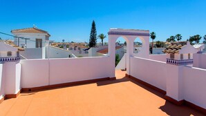 Une terrasse sur le toit offrant une vue dégagée sur les bâtiments environnants et les palmiers.