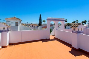 Eine Dachterrasse mit freiem Blick auf die umliegenden Gebäude und Palmen.