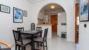 Un coin repas avec une table et des chaises, une cuisine en arrière-plan et des œuvres d’art encadrées accrochées aux murs.