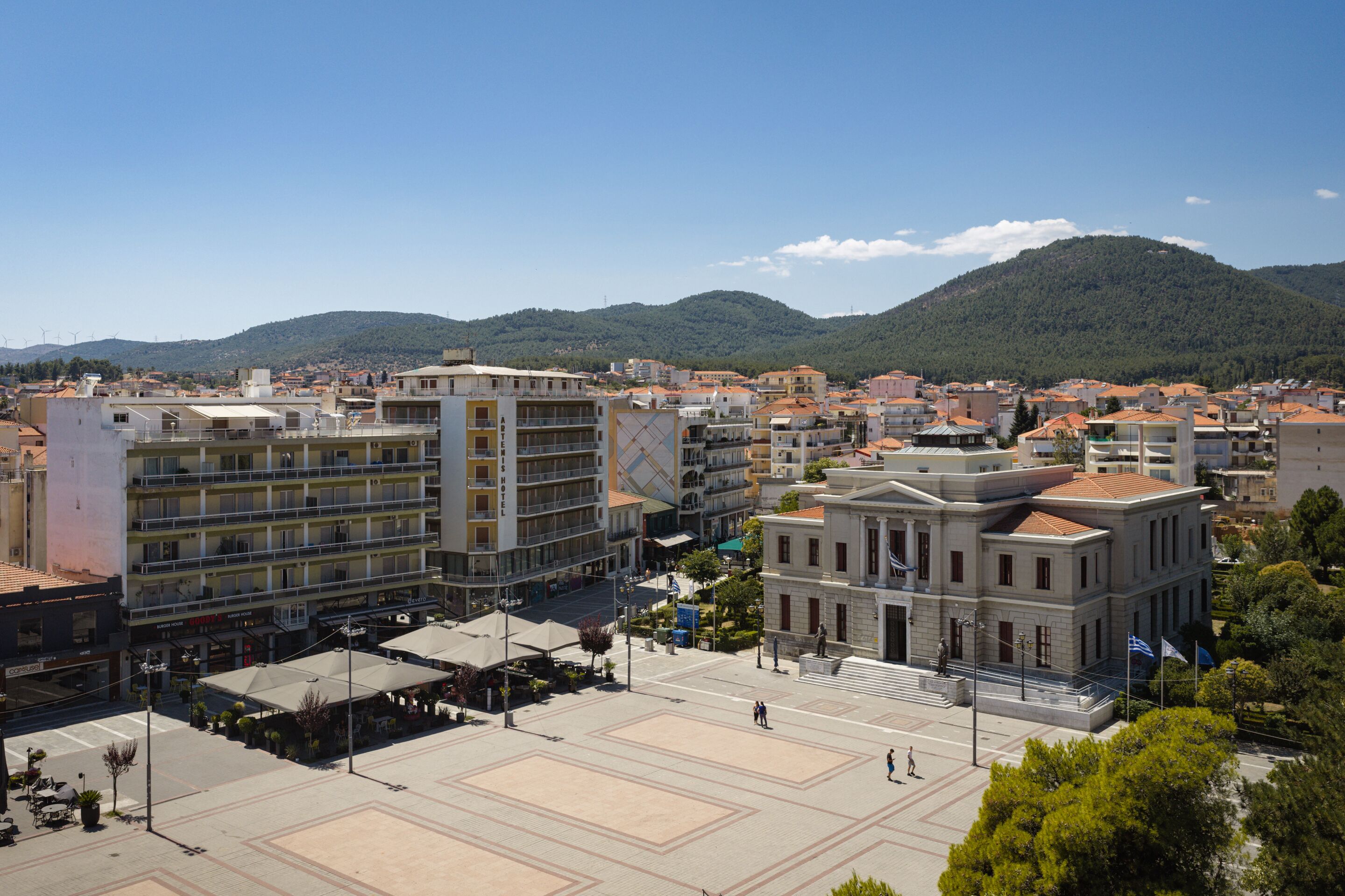 Un hotel con varios pisos, un patio central y montañas al fondo.