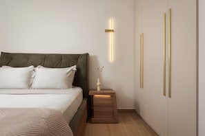 Une chambre moderne avec un grand lit, une table de chevet ornée d’un vase et un luminaire fixé au mur.