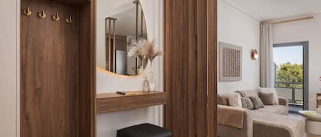 A modern living room with a sofa, a black ottoman, a wooden wardrobe, and a large mirror.