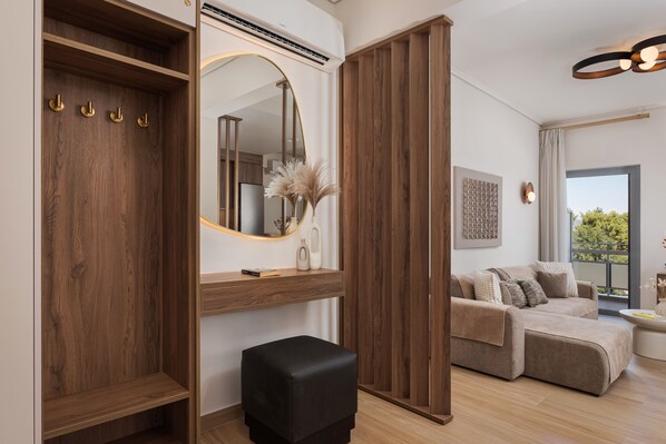 A modern living room with a sofa, a black ottoman, a wooden wardrobe, and a large mirror.