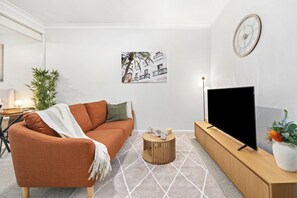 Ein Wohnzimmer mit einer Couch, einem Couchtisch, einem Fernseher und einer Wanduhr.