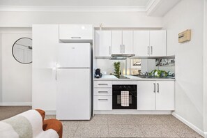 Eine moderne Küche mit weißen Schränken, einem Backofen und einem Kühlschrank.