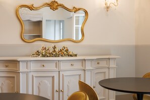 Um quarto com um armário branco, um espelho com moldura dourada e um lustre.