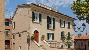 Un bâtiment à deux étages doté d’une entrée centrale, d’un escalier menant à l’étage supérieur et d’un petit balcon avec une balustrade.