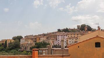 Vista de un pueblo con edificios de tejados de terracota, una destacada torre del reloj y cielo despejado.