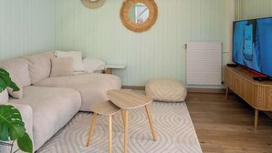 Ein Zimmer mit einer Couch, einem kleinen Holztisch, einem Fernseher und zwei Spiegeln an der Wand.