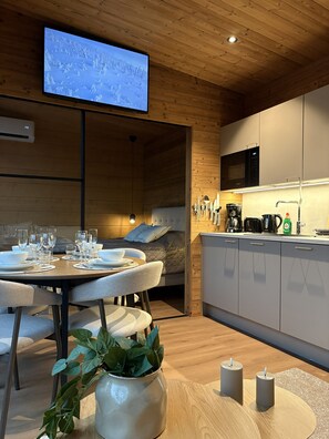 A modern interior with a dining area, kitchen, and a television mounted on the wall.