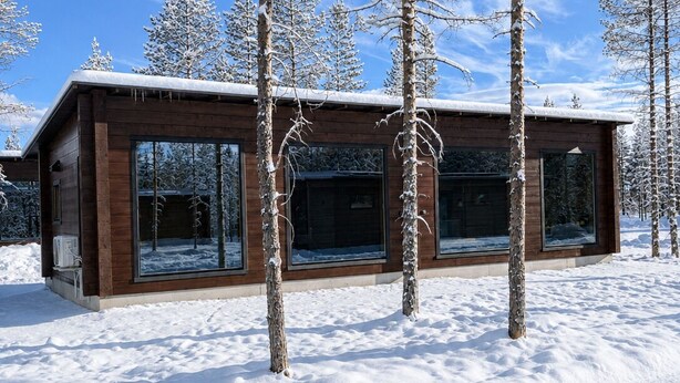 A modern wooden cabin with large windows, surrounded by snow-covered trees. - Arctic Forest Suite with Private Sauna (Rovaniemi)